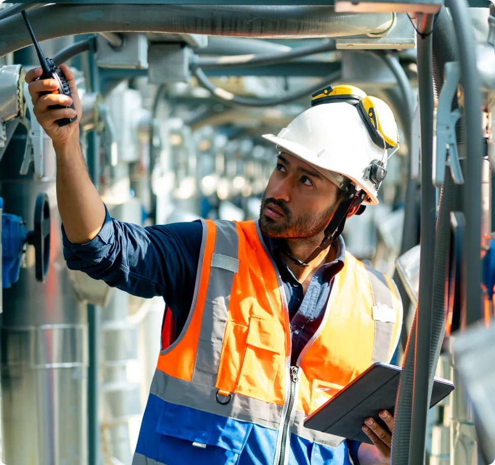Man in a white hard hat hands a radio up to a teammate.